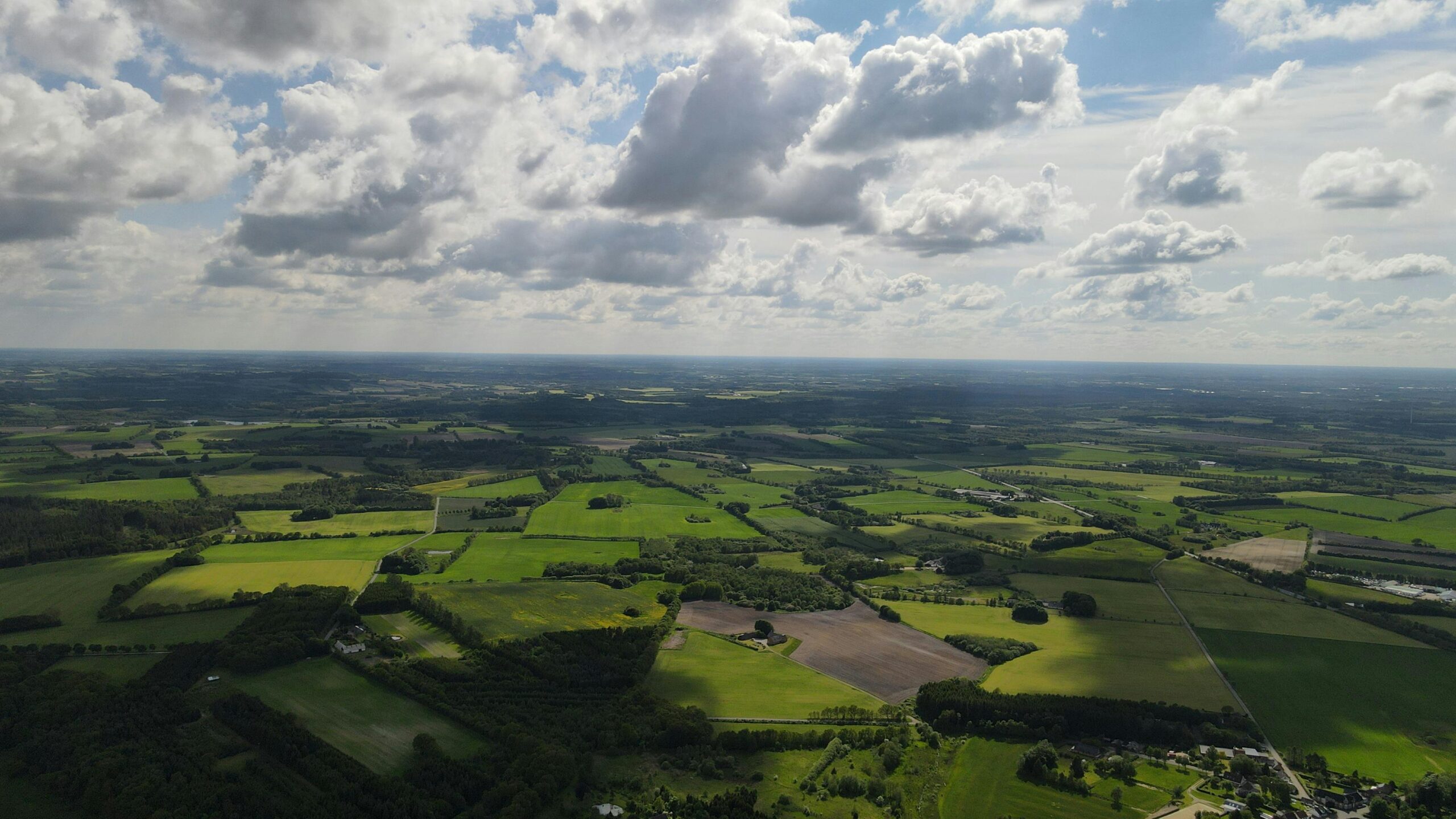 A stunning aerial view of the green farmlands and landscape in Ejstrupholm, Denmark under a clouded sky.